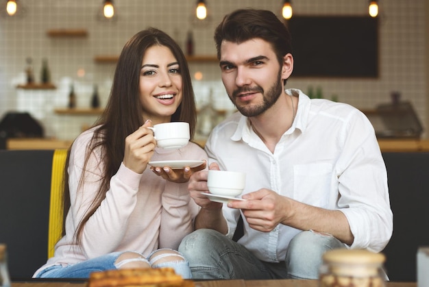 Atmosfera romantica. Coppie caucasiche felici che si siedono nella caffetteria e che bevono caffè