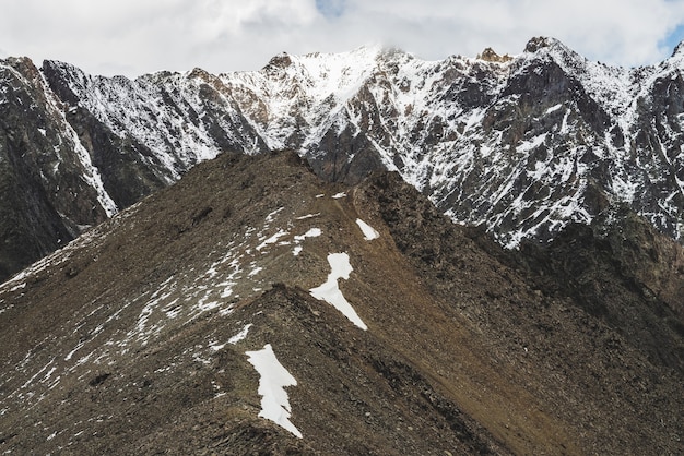 Atmosferico paesaggio alpino minimalista con massiccia catena montuosa innevata e firn sulla collina rocciosa combe