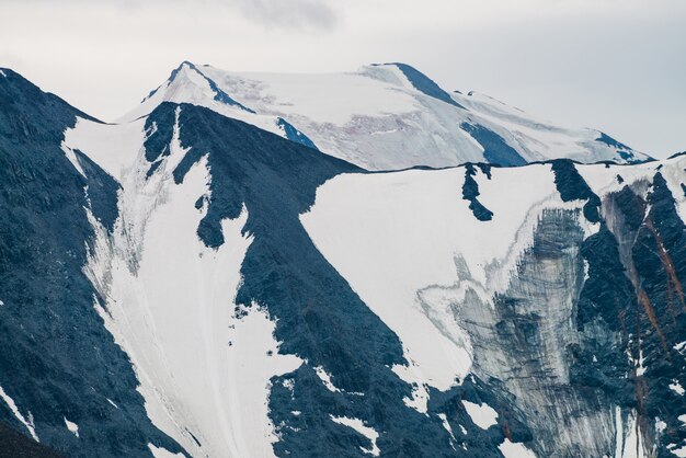 Atmosferico paesaggio alpino minimalista con una gigantesca catena montuosa e un enorme ghiacciaio. Montagne meravigliose con ghiacciai pensili. Grande cresta di montagna innevata. Maestoso scenario degli altipiani in alta quota.