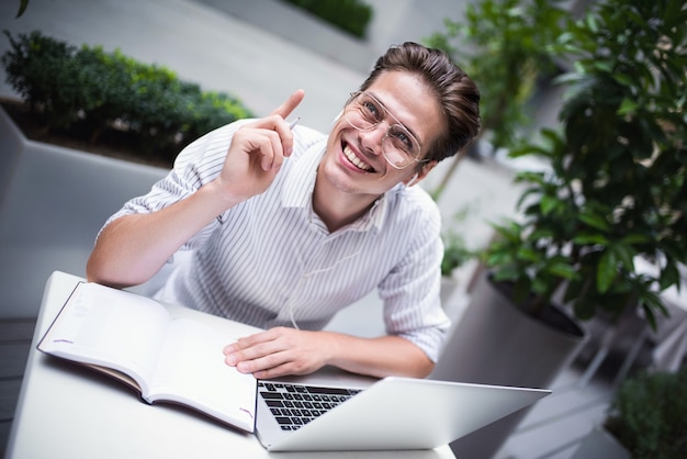 Atteggiamento intelligente Uomo bello e positivo che usa un laptop e si siede al bar mentre naviga in Internet