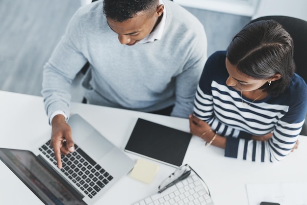 Attenersi a questo metodo ci garantirà sicuramente il successo Inquadratura dall'alto di due giovani uomini d'affari che esaminano figure su un laptop alla scrivania dell'ufficio