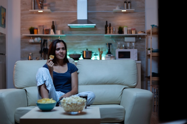 Attento concentrato giovane donna che guarda film mangia spuntini