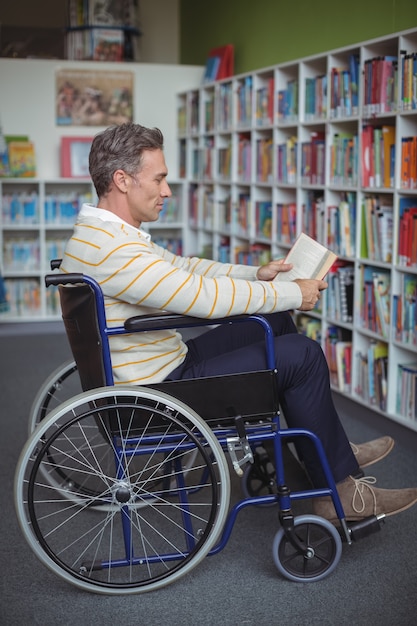 Attento insegnante di scuola disabili leggendo il libro in biblioteca