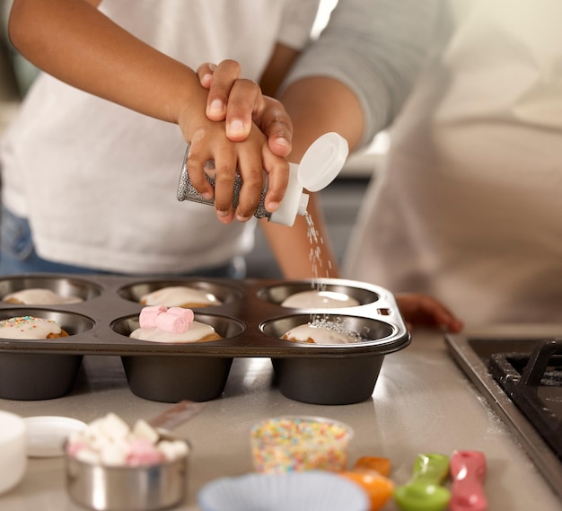 Attento, non troppo, Ritagliata foto di una bambina irriconoscibile che cucina cupcakes con sua madre a casa