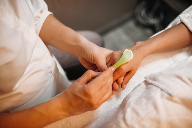 Attento operatore termale sta applicando una crema antietà sulla mano del cliente prima di iniziare il massaggio