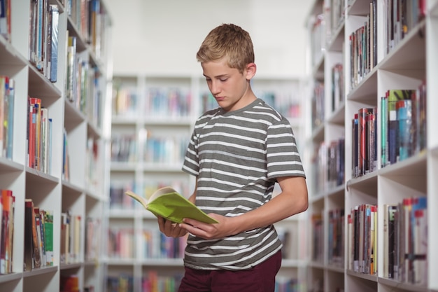 Attento scolaro leggendo il libro in biblioteca