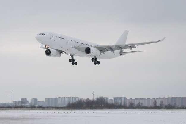 Atterraggio dell'aeroplano bianco del passeggero all'aeroporto nell'orario invernale basso sopra la pista