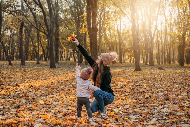 Attività di allontanamento sociale autunnali in famiglia famiglia felice mamma e bambina che giocano all'aperto in