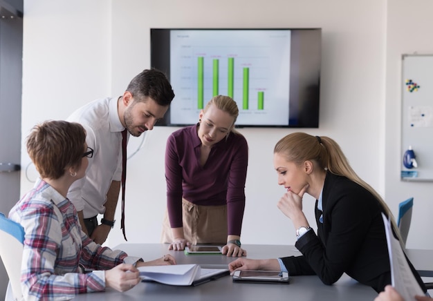 attività di avvio, gruppo di giovani creativi che fa brainstorming sulla riunione in ufficio, utilizzando laptop e tablet per annotare idee, piani e progetti