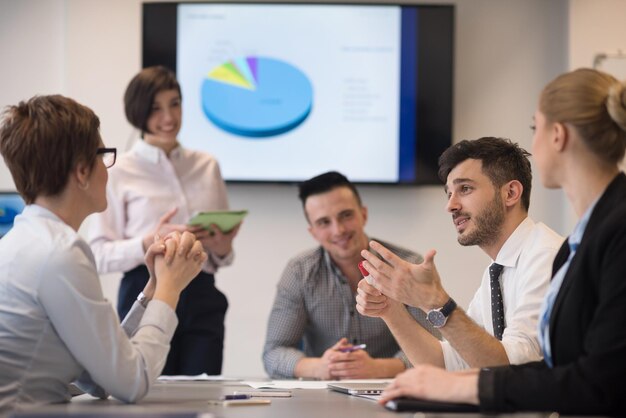 attività di avvio, gruppo di giovani creativi che fa brainstorming sulla riunione in ufficio, utilizzando laptop e tablet per annotare idee, piani e progetti