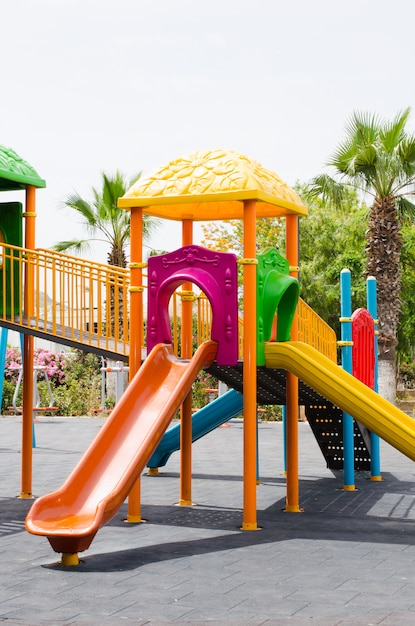 Attività di parco giochi per bambini colorati nel parco pubblico circondato da alberi verdi.