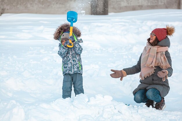 Attività invernali di famiglia mamma e bambino che si divertono insieme sulla neve