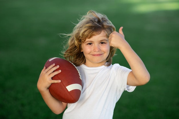 Attività sportive per bambini all'aperto bambino ragazzo con football americano palla da rugby simpatico ritratto di un'america