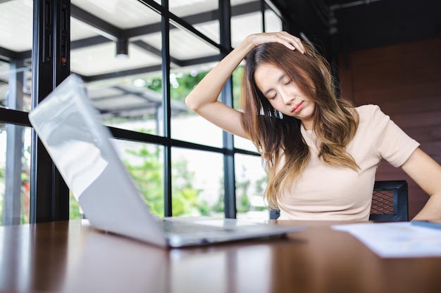 Attraente affari asiatici che sentono dolore al collo dopo aver lavorato a lungo su un computer portatile Concetto di sindrome da ufficio