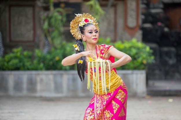 Attraente ballerina balinese lancia fiori di frangipani