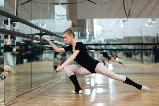 Attraente ballerina che si scalda durante la lezione di balletto