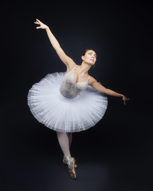 Attraente ballerina posa con grazia su uno sfondo nero