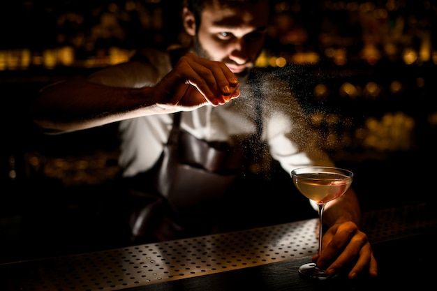 Attraente barista che serve un cocktail nel bicchiere aggiungendo un succo di limone