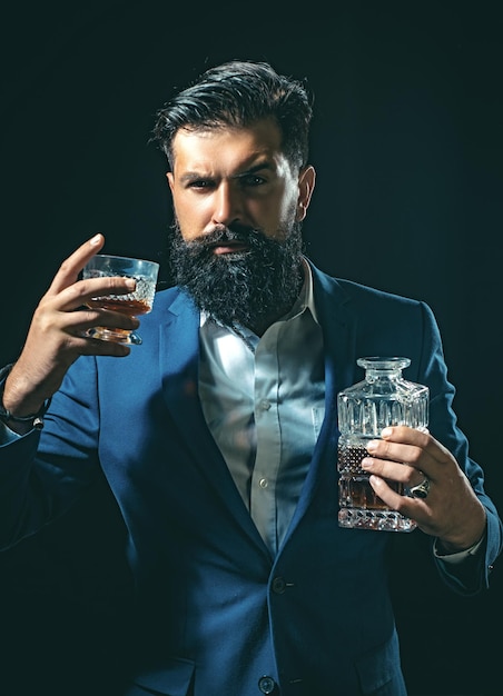 Attraente barista nel whisky bar Uomo ricco e alla moda che tiene un bicchiere di whisky vecchio Uomo con la barba tiene il brandy di vetro