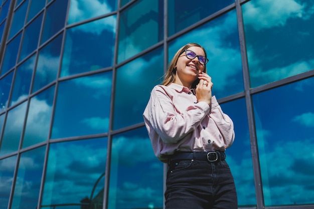 Attraente blogger femminile che tiene in mano un gadget moderno che sembra premuroso e sogna ad occhi aperti giovane blogger in possesso di un telefono cellulare pensando a un'idea da pubblicare sui social media