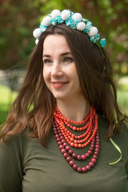 Attraente bruna in un vestito verde con una corona blu e una collana rosa, ritratto