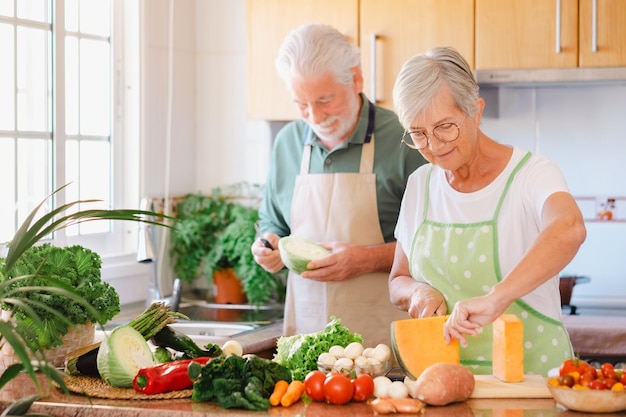 Attraente coppia senior che lavora insieme nella cucina domestica preparando verdure Anziani caucasici sorridenti che si godono uno stile di vita sano e mangiano