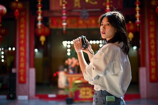 Attraente donna asiatica con la sua macchina fotografica visita un bellissimo tempio cinese durante il suo viaggio