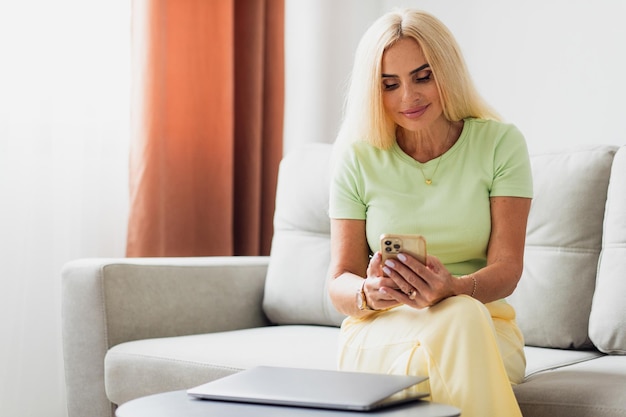 Attraente donna bionda di mezza età utilizza laptop e videochiamata