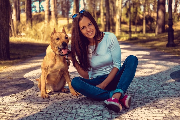 Attraente donna bruna in posa con il suo cane su una strada in una natura primaverile par.