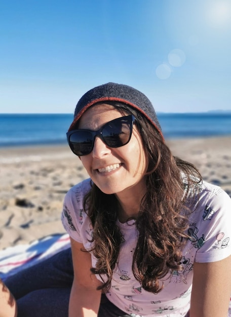 Attraente donna bruna spagnola con occhiali da sole che si gode la pace e la tranquillità sulla spiaggia