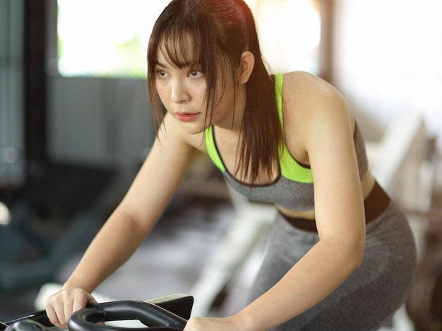 Attraente donna che ha un duro allenamento, in bicicletta sulla macchina per bici fitness presso il centro fitness.