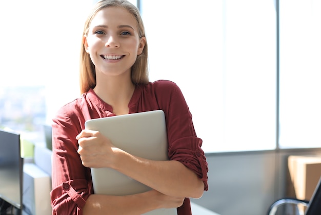 Attraente donna d'affari che guarda l'obbiettivo e sorride mentre si trova in ufficio.