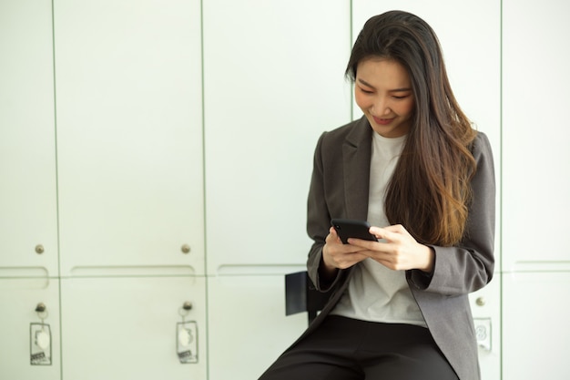 Attraente donna d'affari in abito formale che legge un'e-mail o un messaggio di testo su un telefono cellulare intelligente