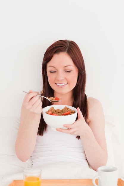 Attraente donna dai capelli rossi con la sua colazione mentre era seduto sul suo letto