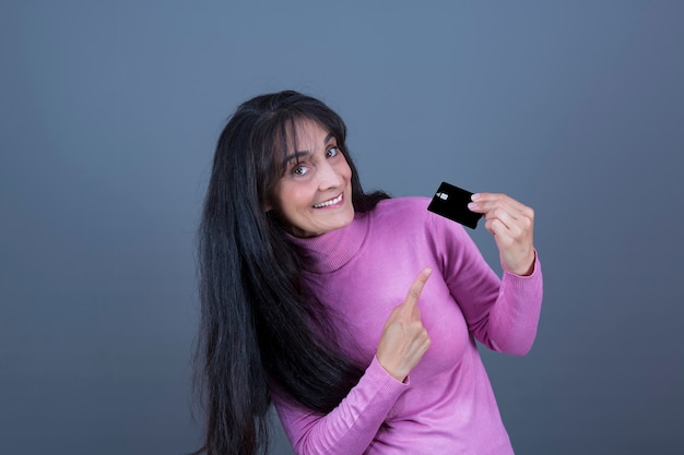Attraente donna di successo dall'aspetto caucasico, bruna dai capelli lunghi che mostra la carta di credito.