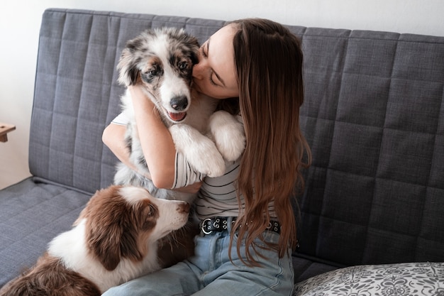 Attraente donna felice bacio Piccolo carino cucciolo di cane pastore australiano blue merle. Concetto di cura degli animali domestici. Amore e amicizia