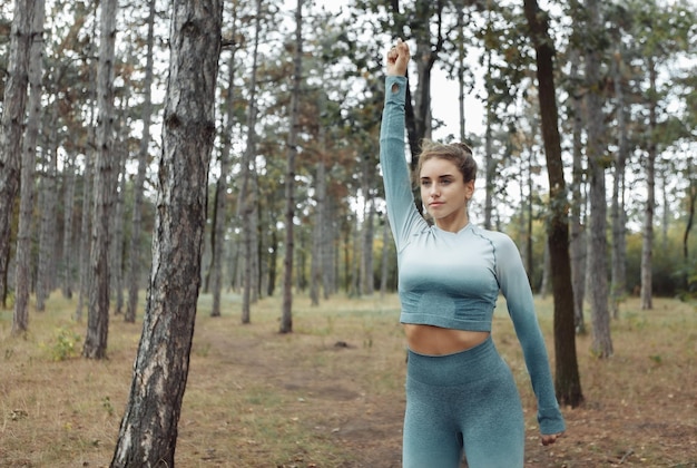 Attraente donna fitness con un corpo perfetto che fa esercizio di riscaldamento o stretching nella foresta Stile di vita sano