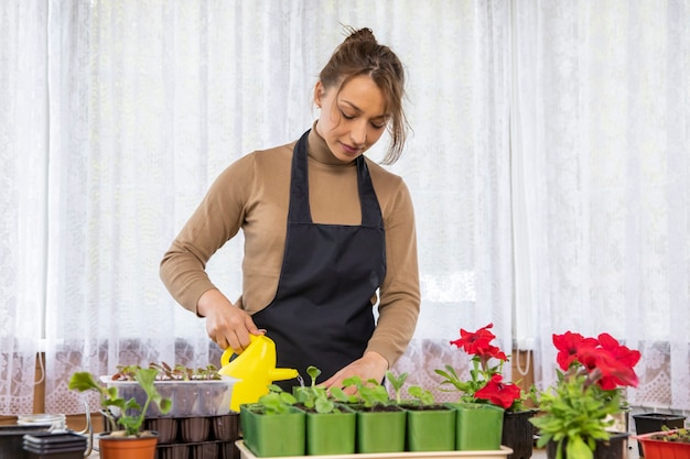 Attraente donna gioiosa positiva che innaffia i fiori con annaffiatoio dopo la semina