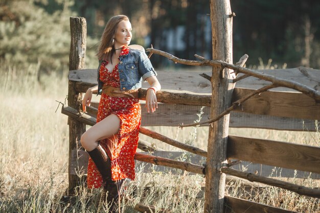 Attraente donna in un abito rosso in campagna
