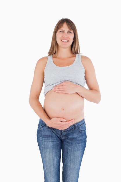 Attraente donna incinta che accarezza la sua pancia mentre in piedi