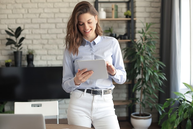 Attraente donna sorridente che lavora su un tablet in un Ministero degli Interni.