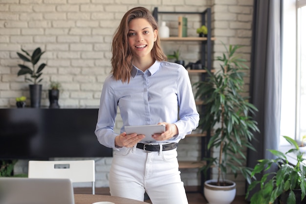 Attraente donna sorridente che lavora su un tablet in un Ministero degli Interni.