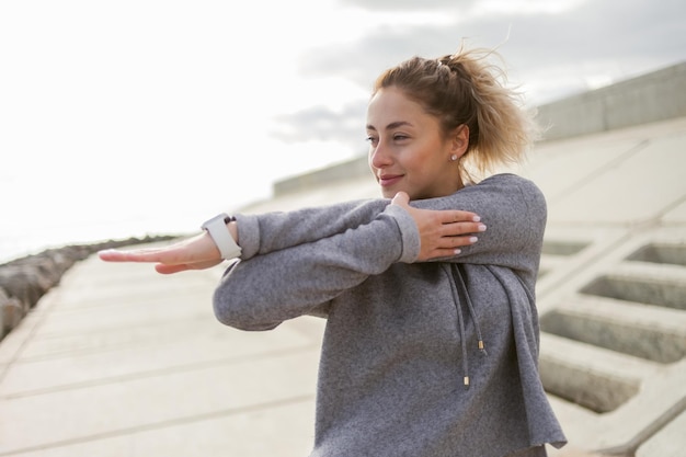 Attraente donna sportiva in abiti sportivi si allena all'aperto Riscaldare o allungare uno stile di vita sano