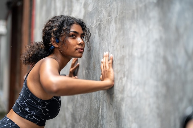 Attraente e forte donna africana che si allunga prima del fitness in città all'aperto Concetto di sport Stile di vita sano