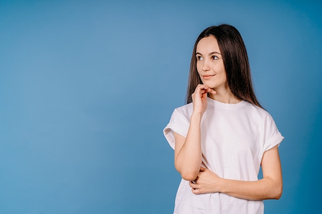 Attraente eccitata giovane donna che indossa abbigliamento casual in piedi isolato sopra la parete blu che guarda lontano