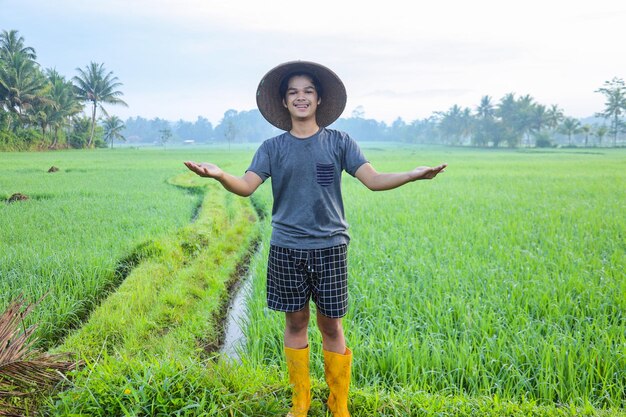 Attraente giovane agricoltore asiatico in piedi sorridente e allargando le braccia che mostrano successo a growi