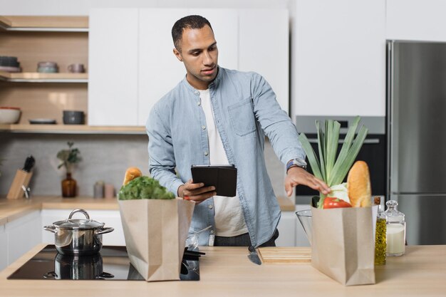 Attraente giovane arabo guardando una ricetta online su una tavoletta digitale