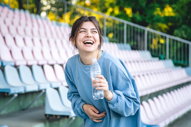 Attraente giovane atleta femminile beve acqua dopo un allenamento