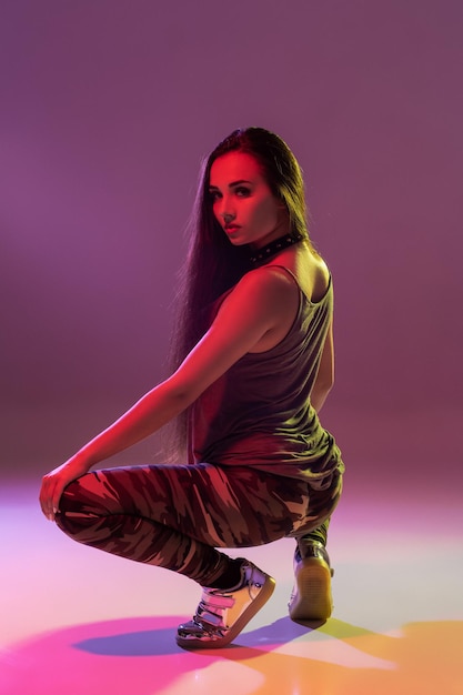 Attraente giovane donna bruna in studio che balla Booty dance su uno sfondo scuro