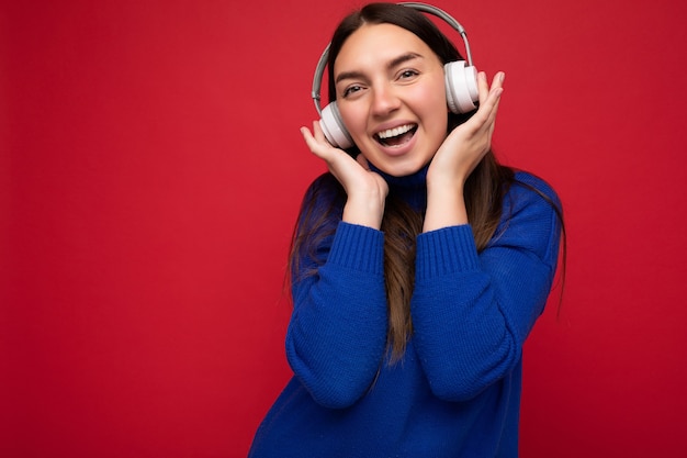 Attraente giovane donna bruna positiva che indossa un maglione blu isolato